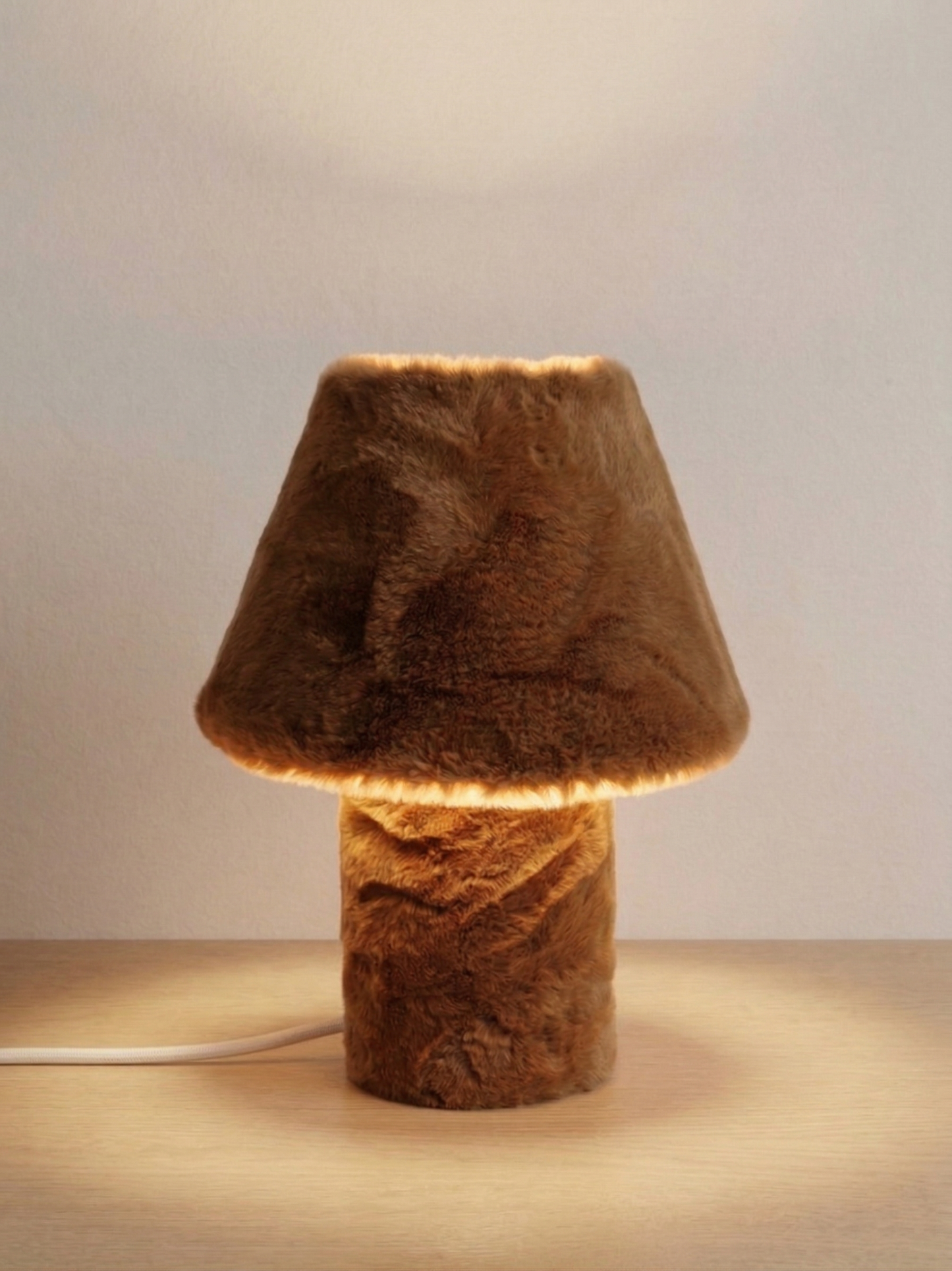 Momo table lamp switched on, casting a warm glow through faux fur