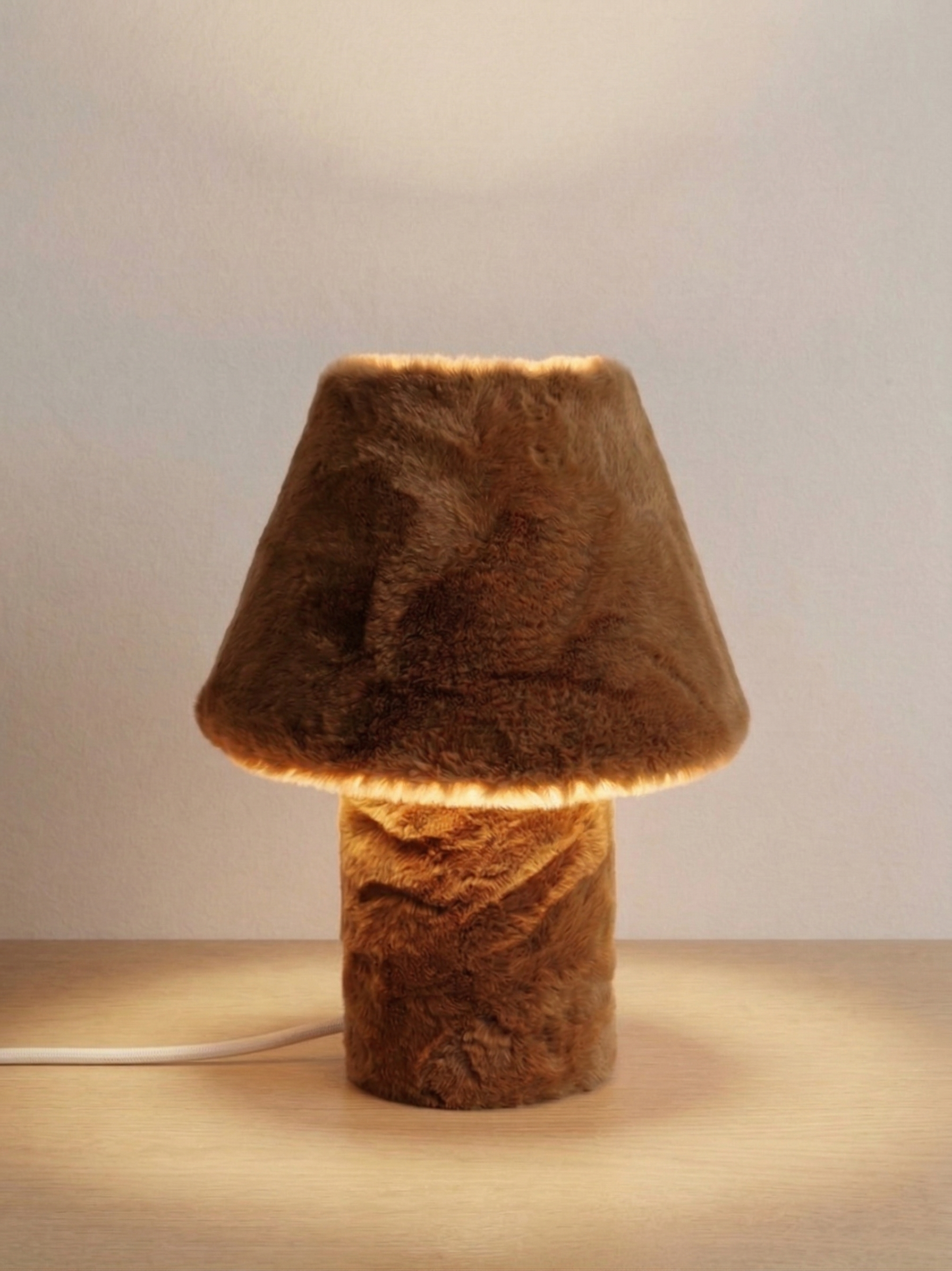 Momo table lamp switched on, casting a warm glow through faux fur