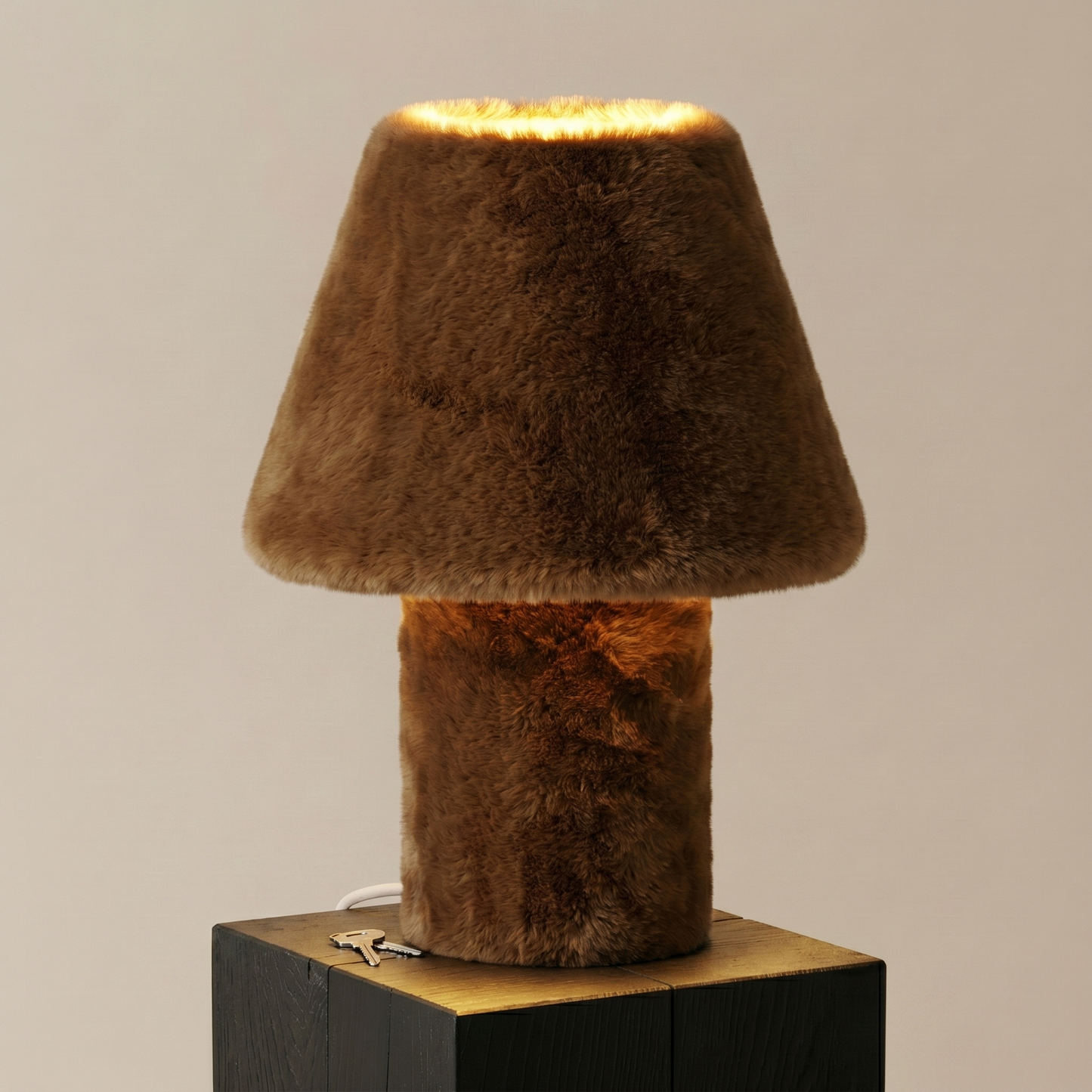 Momo faux fur table lamp glowing on its jesmonite base, side view