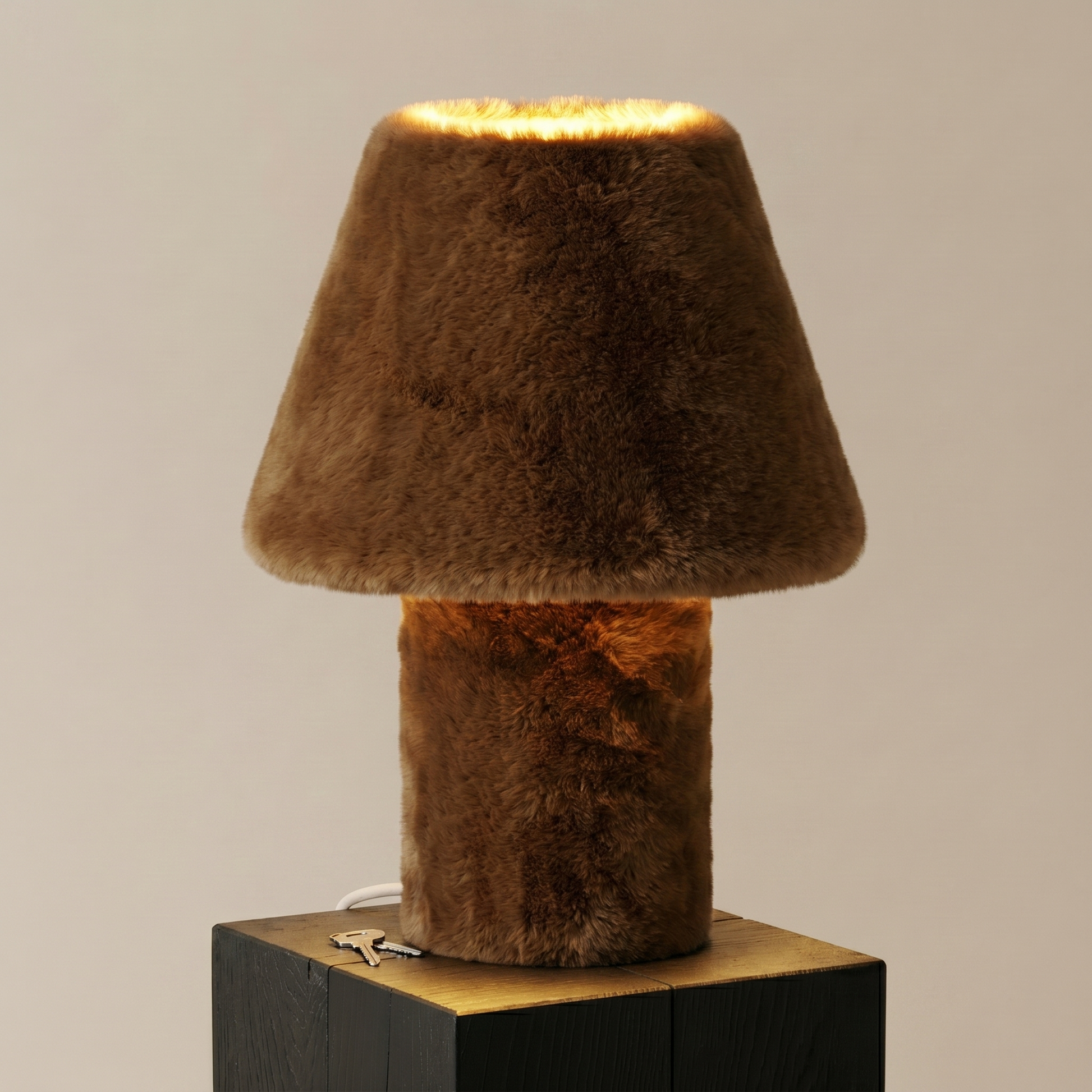 Momo faux fur table lamp glowing on its jesmonite base, side view